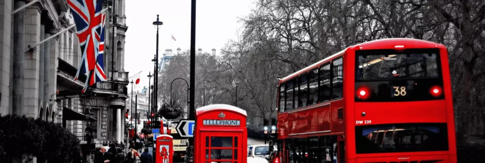Londra'da bir cadde. kırmızı bir otobüs, telefon kulübesi ve binaya asılmış ingiltere bayrağı