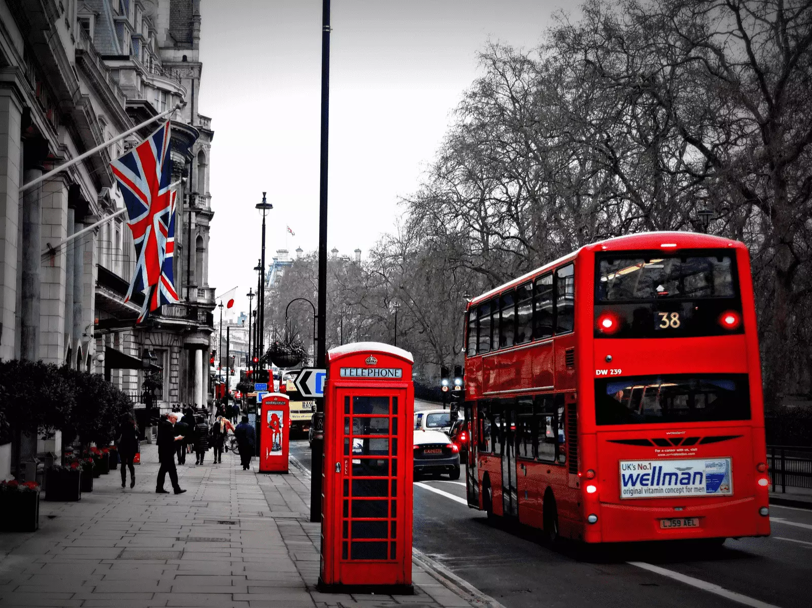 Londra'da bir cadde. kırmızı bir otobüs, telefon kulübesi ve binaya asılmış ingiltere bayrağı